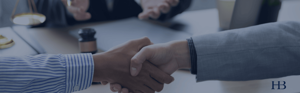 hands shaking in business setting with table in background.